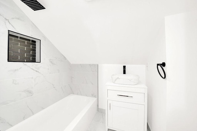 bathroom with vanity, vaulted ceiling, and a tub