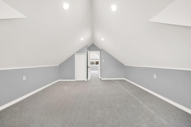 additional living space featuring vaulted ceiling and carpet floors