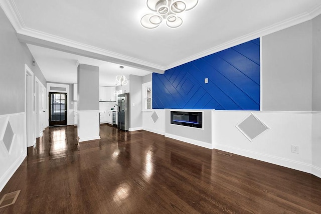 unfurnished living room with dark hardwood / wood-style flooring, crown molding, and a chandelier