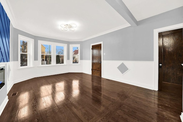 spare room featuring beamed ceiling and dark hardwood / wood-style flooring