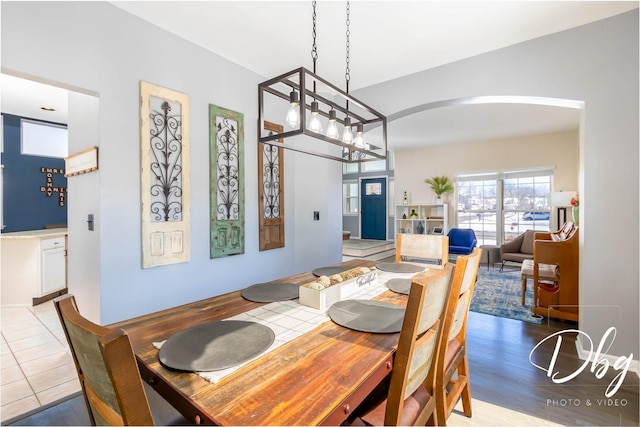 dining room featuring an inviting chandelier, arched walkways, and wood finished floors