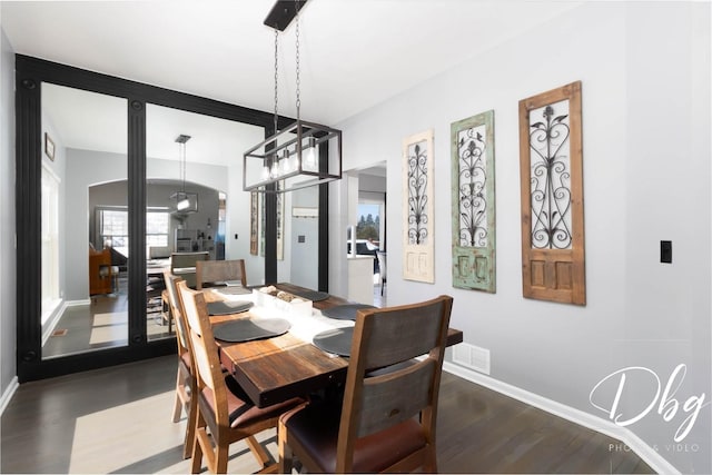 dining room with dark wood-type flooring, visible vents, and baseboards