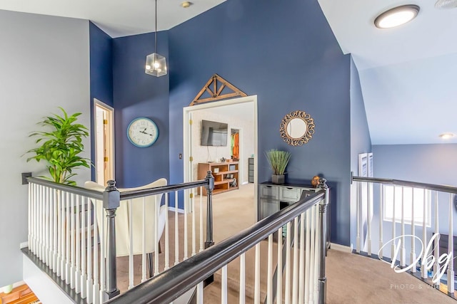 hallway with carpet floors, baseboards, high vaulted ceiling, and an upstairs landing