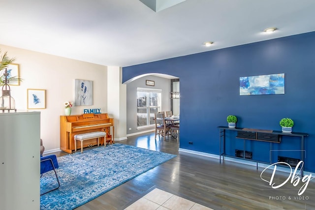 living area featuring baseboards, arched walkways, and wood finished floors