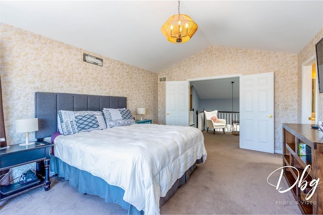 carpeted bedroom with visible vents, vaulted ceiling, and wallpapered walls