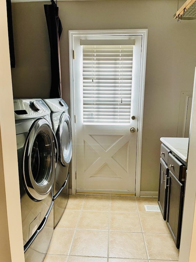 washroom with cabinets, washing machine and clothes dryer, and light tile patterned floors