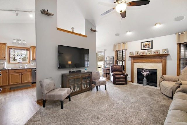 carpeted living room with ceiling fan, a fireplace, high vaulted ceiling, and a healthy amount of sunlight