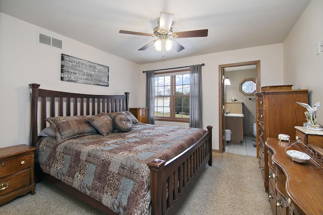 bedroom featuring light colored carpet, ceiling fan, and ensuite bathroom