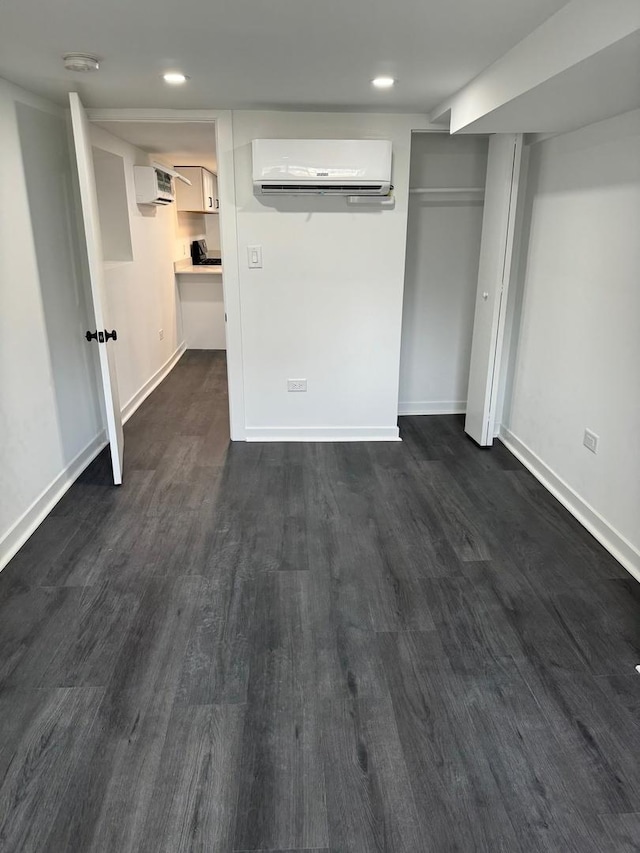 unfurnished bedroom with dark hardwood / wood-style floors, a closet, and an AC wall unit