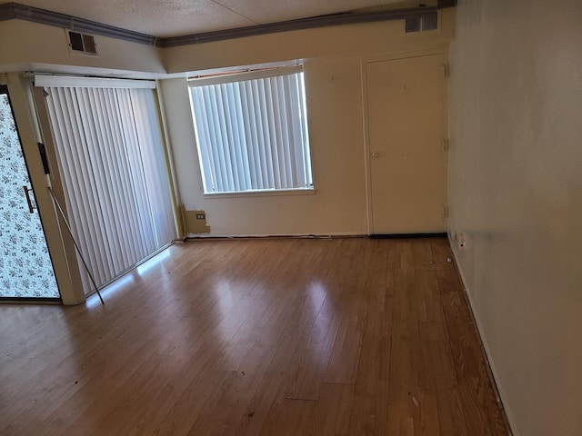 empty room with light hardwood / wood-style flooring and a textured ceiling