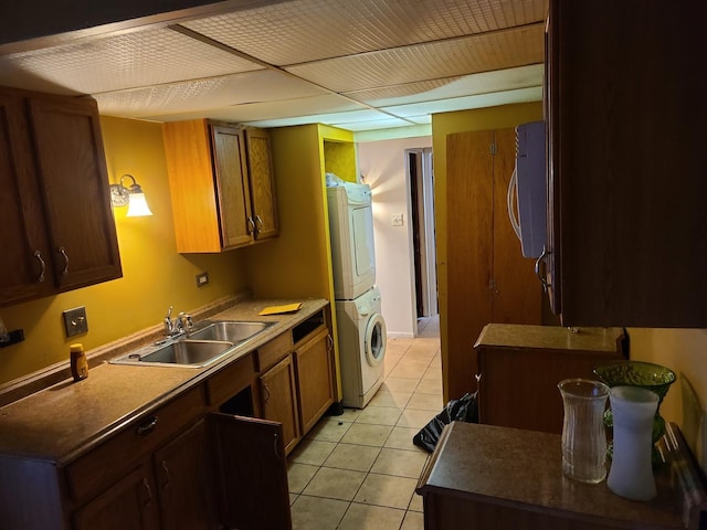 kitchen with sink, light tile patterned floors, and stacked washer / drying machine