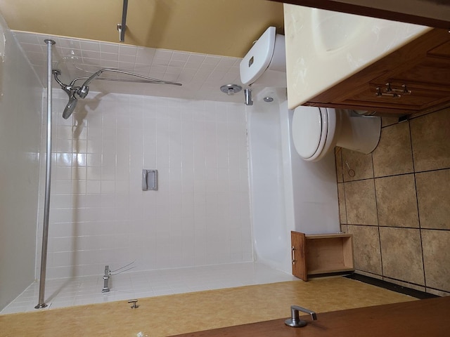 bathroom featuring a tile shower and toilet