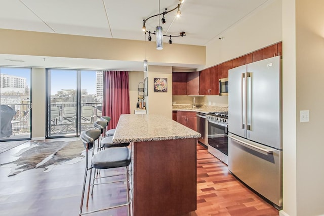 kitchen featuring a breakfast bar area, a center island, hanging light fixtures, appliances with stainless steel finishes, and light hardwood / wood-style floors