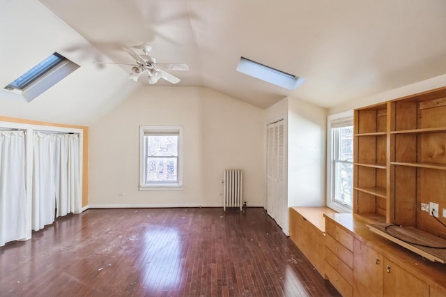 additional living space with lofted ceiling with skylight, plenty of natural light, radiator, and dark hardwood / wood-style flooring