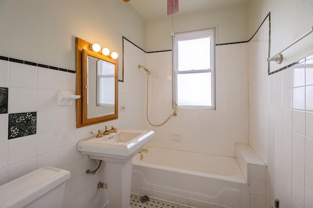 bathroom featuring tiled shower / bath combo, tile walls, and toilet