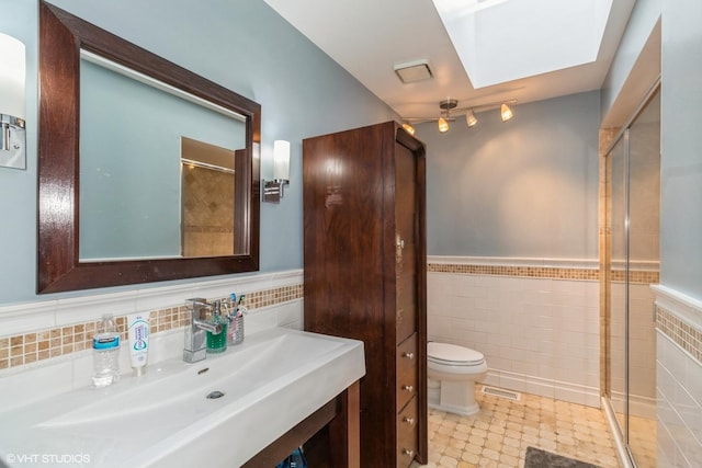 bathroom featuring tile walls, sink, toilet, and walk in shower