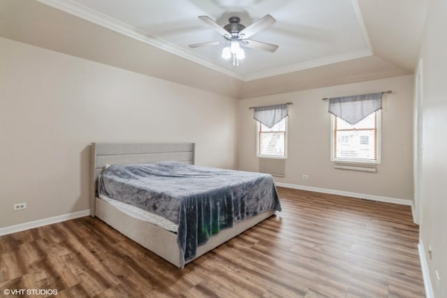 bedroom with hardwood / wood-style flooring, ceiling fan, crown molding, and a raised ceiling