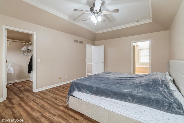 bedroom featuring dark wood-type flooring, connected bathroom, ornamental molding, a spacious closet, and vaulted ceiling