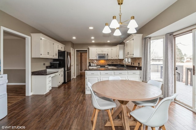 kitchen with decorative light fixtures, white cabinetry, sink, stainless steel appliances, and dark wood-type flooring