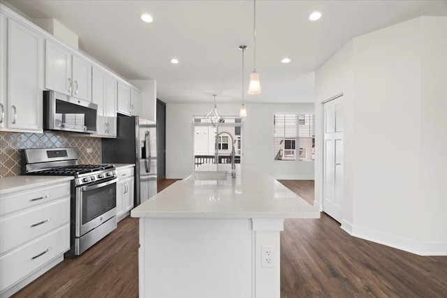 kitchen featuring pendant lighting, an island with sink, white cabinets, and appliances with stainless steel finishes