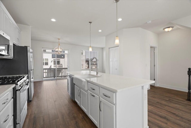 kitchen featuring sink, white cabinetry, hanging light fixtures, a center island with sink, and appliances with stainless steel finishes