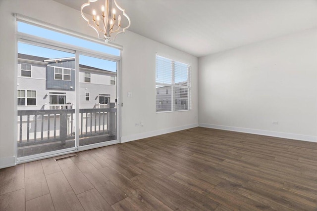 spare room featuring dark hardwood / wood-style floors and an inviting chandelier