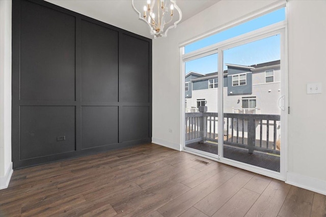 empty room featuring dark hardwood / wood-style floors and a notable chandelier