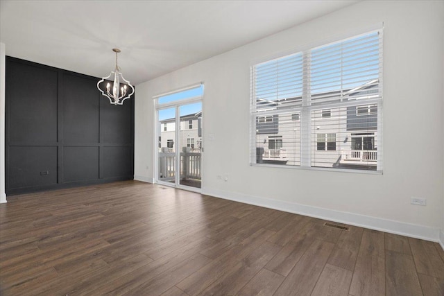 unfurnished dining area featuring dark wood-type flooring and a chandelier