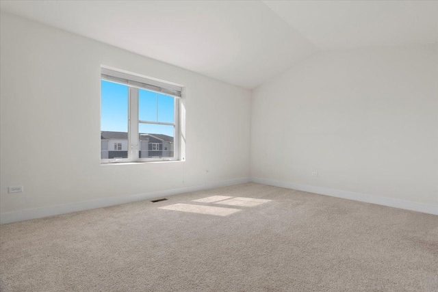 carpeted empty room with vaulted ceiling