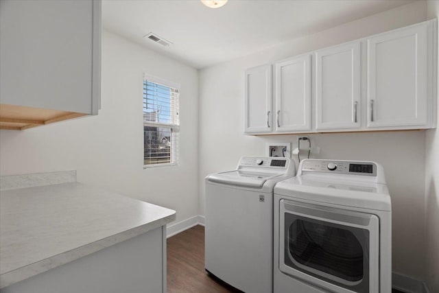 laundry area featuring dark wood-type flooring, cabinets, and washer and clothes dryer