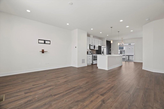 unfurnished living room featuring dark wood-type flooring, sink, and a notable chandelier