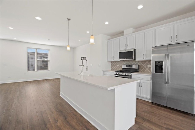 kitchen featuring a kitchen island with sink, hanging light fixtures, stainless steel appliances, and white cabinets