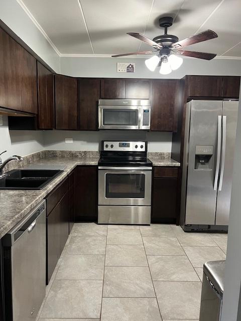 kitchen with light tile patterned flooring, dark brown cabinetry, sink, appliances with stainless steel finishes, and ceiling fan