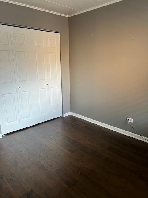 unfurnished bedroom with ornamental molding, dark hardwood / wood-style floors, and a closet