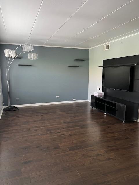 living room featuring dark wood-type flooring and crown molding