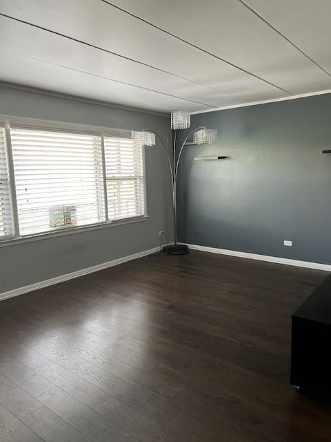 empty room with ornamental molding and dark wood-type flooring