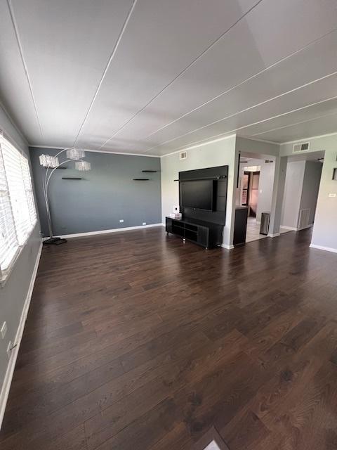 unfurnished living room featuring dark wood-type flooring and an inviting chandelier