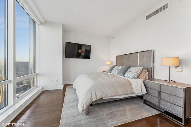 bedroom with multiple windows, dark hardwood / wood-style flooring, and expansive windows