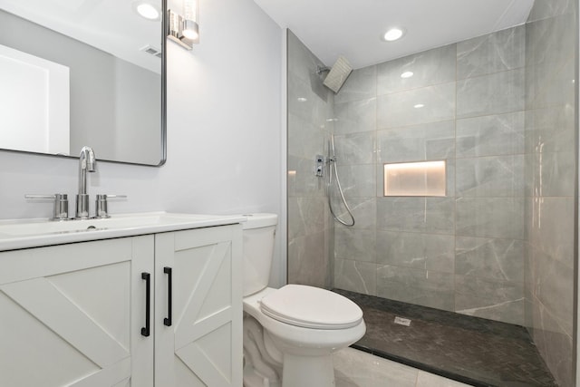 bathroom with tiled shower, vanity, and toilet