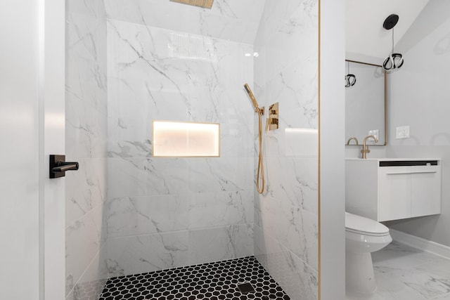 bathroom featuring vanity, a tile shower, and toilet