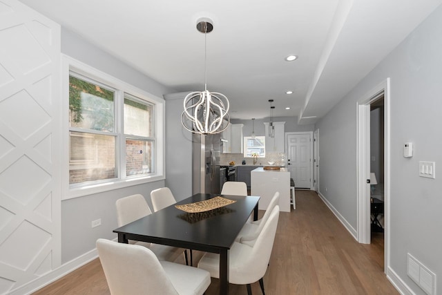 dining space featuring an inviting chandelier and light wood-type flooring