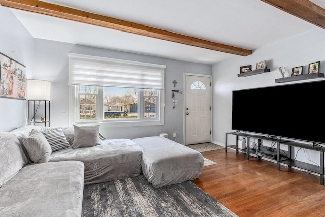 living room featuring beam ceiling, baseboards, and wood finished floors