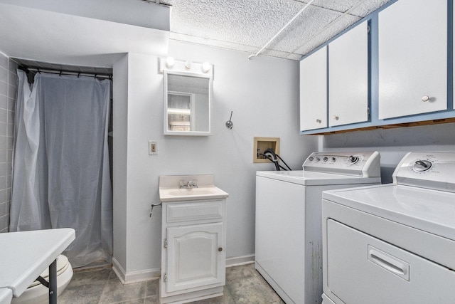 washroom with laundry area, a sink, baseboards, and separate washer and dryer