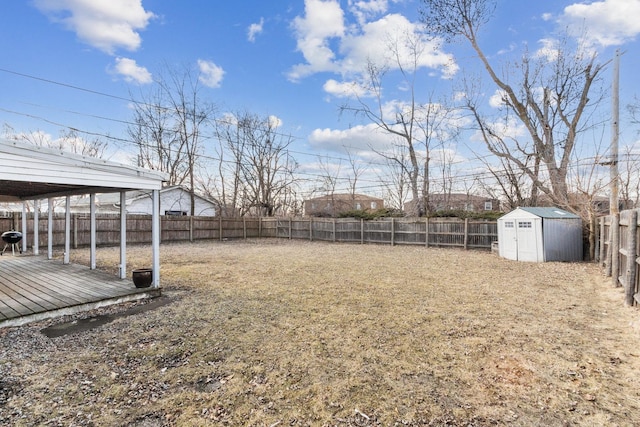 view of yard with a fenced backyard, an outdoor structure, a deck, and a shed