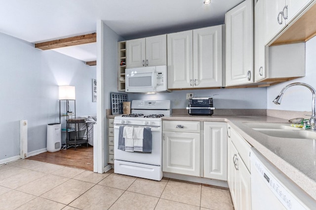 kitchen with light tile patterned floors, white appliances, a sink, white cabinets, and light countertops