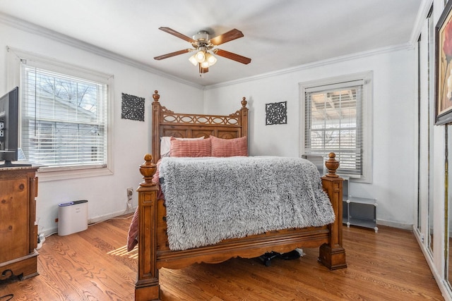 bedroom featuring baseboards, crown molding, and light wood finished floors