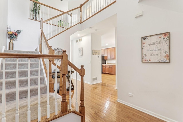 staircase featuring a high ceiling and hardwood / wood-style floors