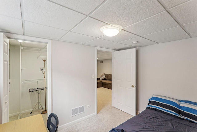 bedroom with a drop ceiling and light carpet