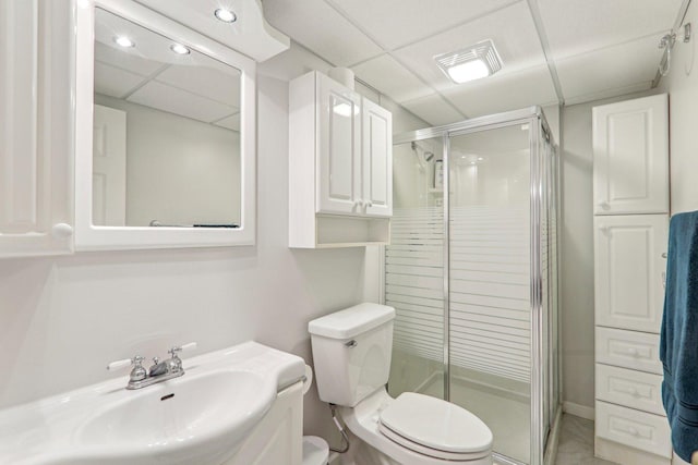 bathroom with sink, a shower with shower door, toilet, and a paneled ceiling