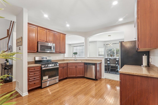 kitchen featuring pendant lighting, stainless steel appliances, light hardwood / wood-style floors, and sink